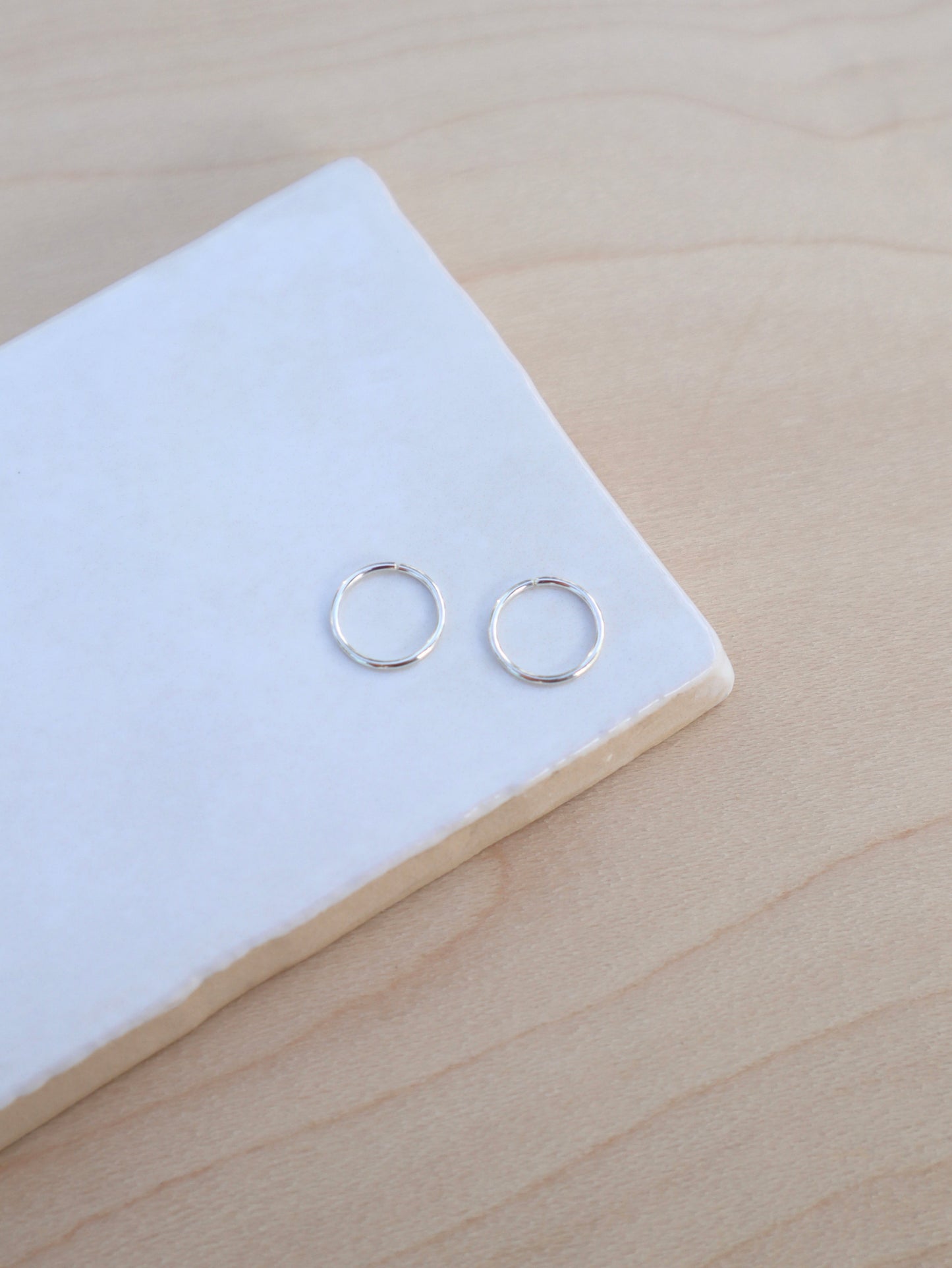 A pair of mini silver wire hoop earrings.
