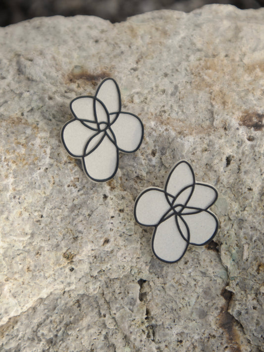 Handmade floral stud earrings with hand-painted outline design on natural stoneware.