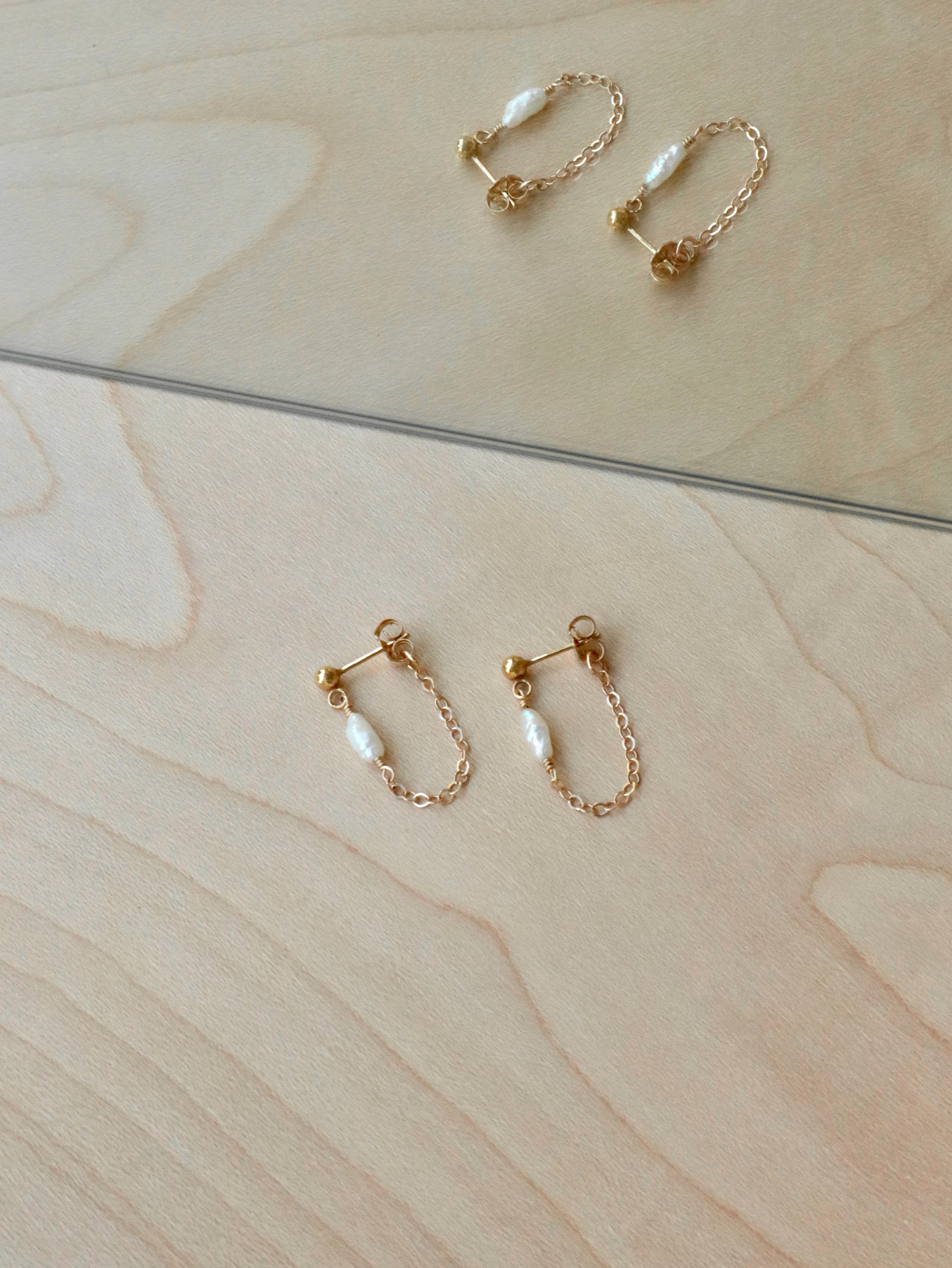 Gold chain earrings with tiny, oblong, irregular pearls. The flat cable chain sparkles as it catches the light.